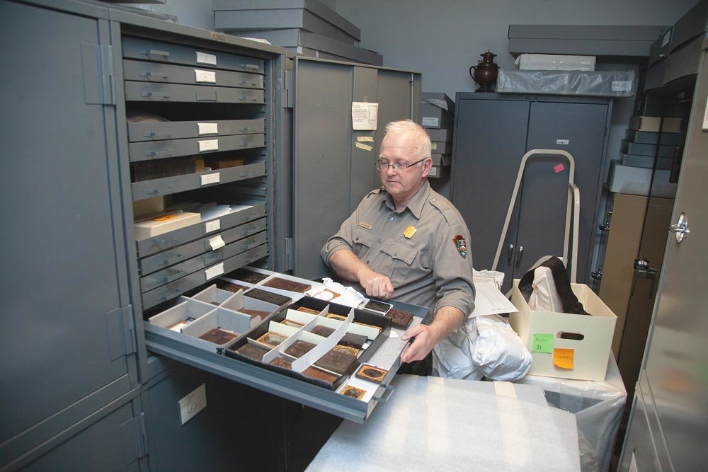 PRESERVING HISTORY: Museum curator Jeff Patrick goes through artifacts, such as artillery from the 1860s, stored in drawers and cabinets in the park’s library due to lack of exhibit space.